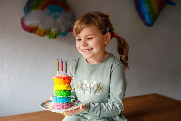 誕生日を祝う幸せな小さな就学前の女の子 手作りの虹のケーキ 屋内でかわいい笑顔の子供 幸せな健康な幼児吹いて6キャンドルオンケーキ — ストック写真
