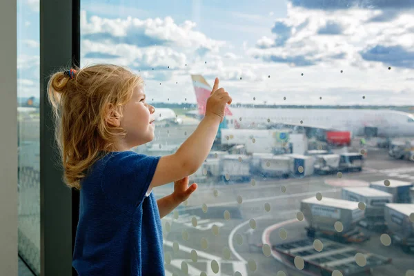 空港でかわいい幼児の女の子 窓の近くで待っている幸せな健康な子供と飛行機を見て 飛行機で夏休みに行く家族 — ストック写真