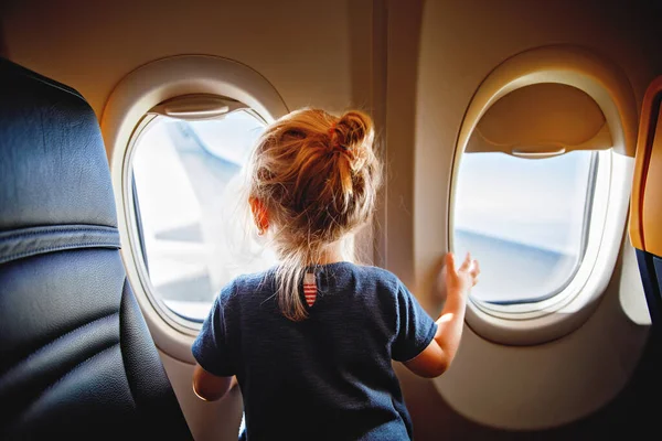 可爱的小女孩坐飞机旅行 小孩坐在飞机窗前 看着外面 和孩子们一起出国旅行暑假的家庭 — 图库照片