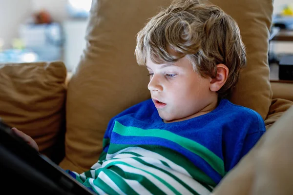 带着平板电脑的男生学童在网上学习 在家里学习 学习和玩耍的电子设备 带着手提电脑的小男孩 为儿童提供小工具和屏幕时间 孩子在家里 — 图库照片