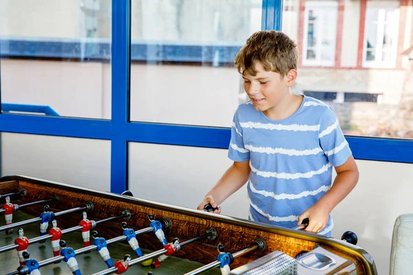 stock image Smiling school boy playing table soccer. Happy excited child having fun with family game with siblings or friends. Positive kid