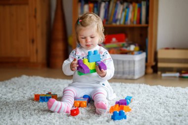 Sevimli Bebek Kız Çocuk Yuvasında Eğitici Oyuncaklarla Oynuyor. Mutlu Sağlıklı Çocuk Renkli Farklı Plastik Bloklarla Evde Eğleniyor. Şirin Bebek Öğrenme, Yaratma ve İnşaat