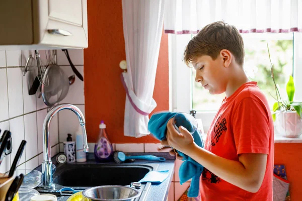 英俊的少年用毛巾擦干干净的盘子 十几岁的孩子在厨房帮忙做家务活 — 图库照片