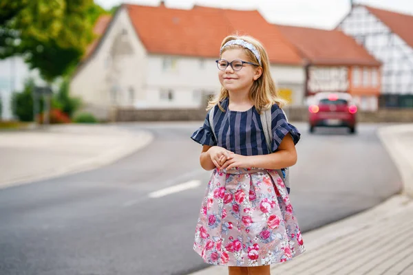 小女孩在去学校的路上 健康快乐儿童步行至幼儿园及幼稚园 带着眼镜和背包在市郊大街上微笑的孩子 回学校去 — 图库照片