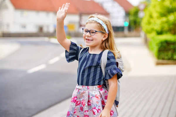 小女孩在去学校的路上 健康快乐儿童步行至幼儿园及幼稚园 带着眼镜和背包在市郊大街上微笑的孩子 回学校去 — 图库照片