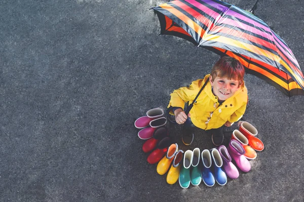 子供リトルボーイとカラフルな長靴のグループ 傘の下で立っている金髪の子 Schoolkid と高角度から異なるゴム長靴のクローズ アップ 雨の落下のためのシューズ — ストック写真