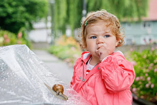 一个可爱可爱的小女孩发现蜗牛在散步 美丽的卷曲的小孩在雨天玩得开心 带大雨伞 穿防水衣服的孩子 — 图库照片
