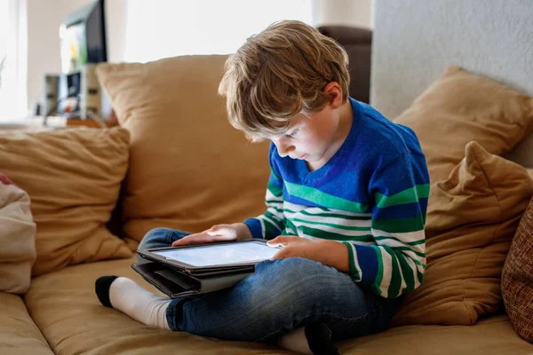 带着平板电脑的男生学童在网上学习 在家里学习 学习和玩耍的电子设备 带着手提电脑的小男孩 为儿童提供小工具和屏幕时间 孩子在家里 — 图库照片