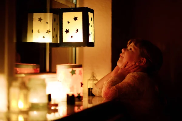小女孩坐在窗边 手里拿着自制的灯笼和蜡烛 为圣马丁游行 蹒跚学步的孩子看着闪闪发光的灯笼 德国传统Martinsumzug 家庭装修 — 图库照片