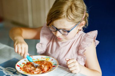 Little preschool girl eating from spoon vegetable potato soup. Healthy food for children. Happy kid at home or nursery