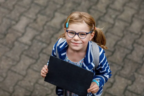 快乐的小女孩手里拿着黑板站在那里 空白板的复制空间 在绿地公园 健康的学龄前儿童在户外戴着眼镜 — 图库照片