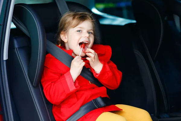 Pequeña Niña Sentada Asiento Del Coche Sosteniendo Dulce Piruleta Contra —  Fotos de Stock