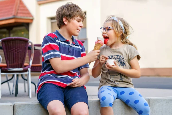 ワッフルコーンでアイスクリームを食べる小さな就学前の女の子と学校の少年幸せな子供たち 弟と妹はアイスクリームデザートを食べます 市内の家族 恋の兄弟 — ストック写真