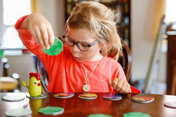 家庭在家里玩棋盘游戏 孩子们玩战略游戏 妹妹移动部分的桌球游戏 有趣的室内活动 兄弟姐妹的结合 教育玩具 — 图库照片