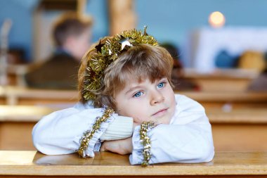 Güzel bir çocuk çocuk Noel hikaye bir kilisede bir melek oynarken. Işıkları ve xmas ağacı arka plan üzerinde mutlu sevimli sarışın çocuk. Xmas gecesi, büyük Hıristiyan, Katolik tatil kutlamaları