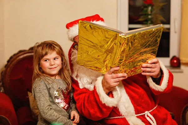サンタクロースと話している少女はドイツ語でニコラウスやヴァインヒャクツマンと呼ばれていた 幸せな笑顔の子供の贈り物を待っている 黄金の本でサンタ クリスマス 子供時代 — ストック写真