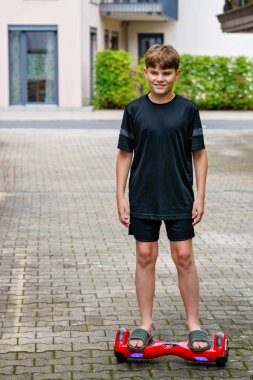 Aktif ergen çocuk havada asılı duruyor. Genç Çocuk, modern denge kaykayı kullanıyor. Egzersiz ve çocuklar için spor, çocuklar için açık hava aktivitesi