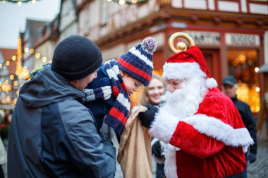 Noel pazarında babası olan küçük bir çocuk. Mutlu çocuk Noel Baba 'dan hediye alıyor. Gülümseyen adam ve oğul, geleneksel bayramı kutlayan aile..