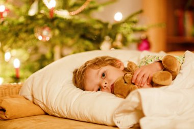 Noel ağacının altında uyuyan ve Noel Baba 'yı evde, evde hayal eden tatlı sarışın çocuk. Geleneksel Hıristiyan festivali. Mutlu çocuk Noel 'de hediye bekliyor. Samimi yumuşak ışık.