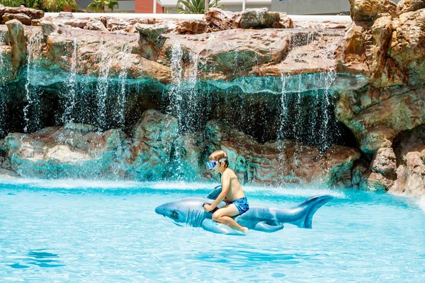 プールでジャンプし ホテルのリゾートで家族の休暇を楽しんで幸せな小さな少年 膨脹可能なサメのおもちゃと水で遊ぶ健康な子供 — ストック写真