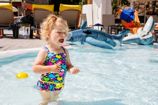 ホテルのリゾートで家族の休暇でプールで小さな幼い子供の少女を泣かすUpset 水中で遊んでいる子供 カラフルなファッション水着の赤ちゃん — ストック写真