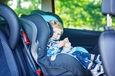 Mavi gözlü sevimli kız bebek emniyet koltuğunda oturuyor. Küçük çocuk aile tatiline ve Jorney 'e gidiyor. Trafik sıkışıklığı sırasında gülümseyen mutlu çocuk, bisküvi yiyor..