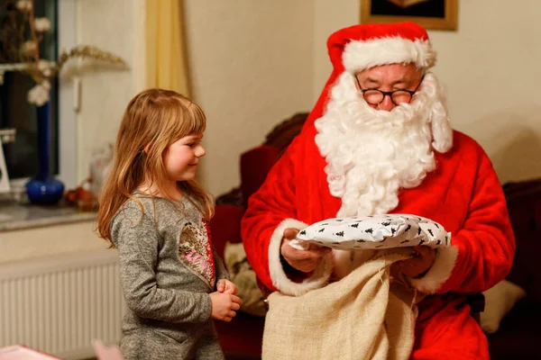 与圣诞老人交谈的小女孩用德语叫Nikolaus或Weihnachtsmann 快乐的微笑着等待礼物的孩子 圣诞老人与黄金书 圣诞节 — 图库照片