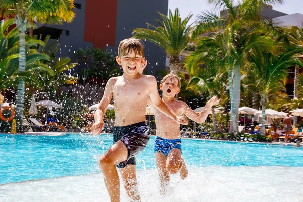 プールでジャンプし ホテルリゾートで家族の休暇を楽しむ2人の幸せな小さな男の子 水銃で遊んでいる子供たち 兄弟姉妹と親友を走らせる笑い — ストック写真