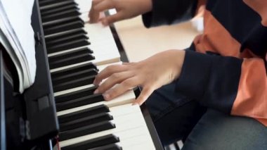 Oturma odasında piyano çalan öğrencinin yakın çekimi. Çocuk müzik aleti çalmayı öğrenirken eğleniyor. Yetenekli genç kız içeride..