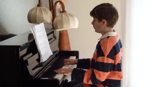 リビングルームでピアノを弾く少年 楽器を演奏することを学ぶことと楽しい子供 才能のある子供 ティーンエイジャー ストック動画