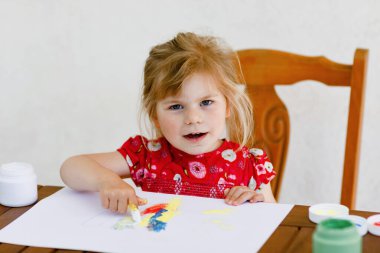 Küçük yaratıcı kız parmak boyasıyla balık boyuyor. Aktif çocuk evde çizim yaparken eğleniyor, anaokulunda ya da anaokulunda. Çocuklar için eğitim ve uzak mesafe eğitimi. Creaitve etkinliği