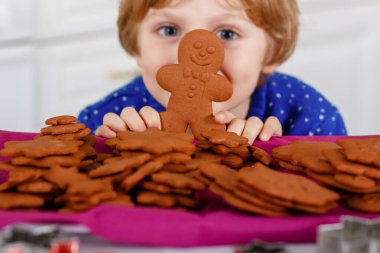 Kreş çocuğu zencefilli kurabiye pişiriyor. Xmas süveter giyen mutlu, yeni yürümeye başlayan çocuk. Mutfak Noel için dekore edildi. Noel aile aktivitesi.