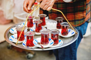 Metal tepside geleneksel cam bardaklarda Türk çayı. İstanbul, Türkiye, Grand Bazaar 'da sıcak çay satan sokak satıcısı