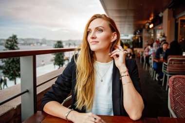Young business woman drinking alcoholic cocktail. Happy alone woman in outdoor cafe or restaurant on sunny summer day, break for lunch between meetings