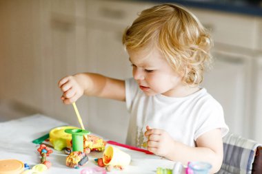 Renkli killi, sevimli, küçük bir kız. Sağlıklı bebek oyun oynuyor ve oyun hamurundan oyuncaklar yapıyor. Küçük çocuk kil kalıp ve öğrenim.