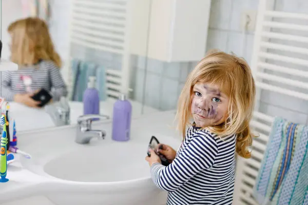 可爱的小女孩用妈妈的妆容 用眼影画着脸 快乐的婴儿用母亲的化妆品做实验 开玩笑吧 — 图库照片