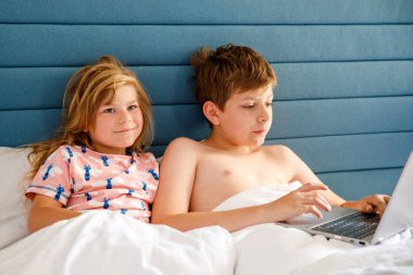 İki çocuk, küçük kız ve okul çocuğu evde internetten öğreniyor. Çocuklar, kardeşlerin evde eğitim ve uzak eğitim için dizüstü bilgisayar kullanması. Erkek ve kız kardeş defterle eğleniyor.