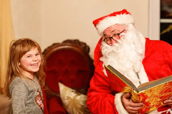 Nikolaus veya Weihnachtsmann adında Almanca Noel Baba 'yla konuşan küçük bir kız. Mutlu gülümseyen çocuk hediye bekliyor. Altın kitaplı Noel Baba. Xmas, çocukluk, tatil.