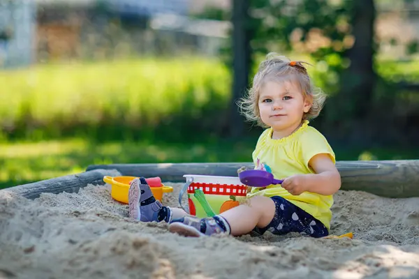 屋外の遊び場で砂の中で遊んでいる幸せな幼児の女の子 晴れた夏の晴れた日に楽しい時間を過ごしている赤ちゃん 砂のおもちゃとカラフルなファッションの服でアクティブな子供 — ストック写真