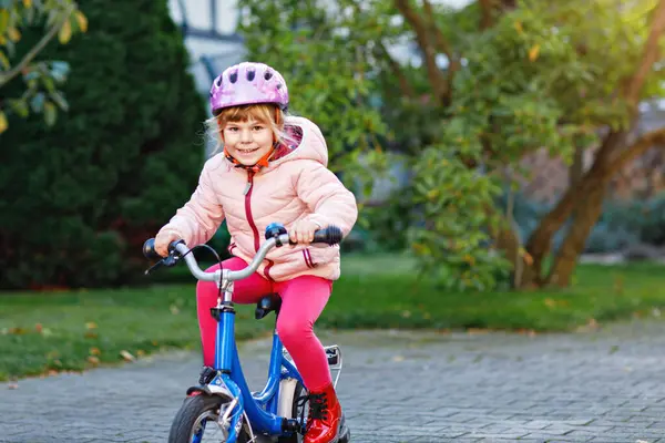学龄前小女孩骑自行车 孩子在户外骑自行车 在温暖的夏日 快乐的孩子在上学的路上骑自行车 学龄前儿童学习骑自行车时戴安全帽保持平衡 — 图库照片
