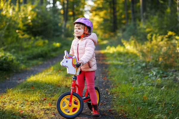 孩子们骑平衡自行车 孩子们骑自行车在阳光灿烂的森林里 小女孩喜欢在暖和的天气里骑滑翔机 学龄前儿童学习如何在安全的头盔中骑自行车保持平衡 体育活动 — 图库照片