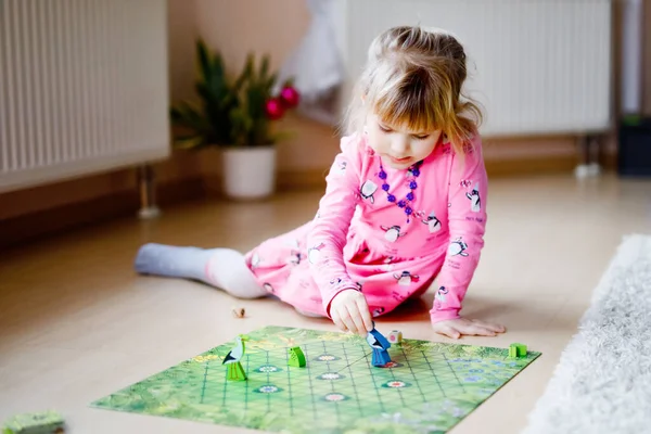 Adorable cute toddler girl playing picture card game. Happy healthy child training memory, thinking. Creative indoors leisure and education of kid during pandemic coronavirus covid quarantine disease.