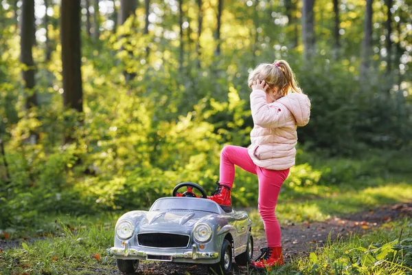 幼儿园的小女孩开着老式的大玩具车 快乐的孩子在外面玩得很开心 活跃的学龄前儿童在森林里享受着温暖的秋天 笑得惊心动魄 — 图库照片