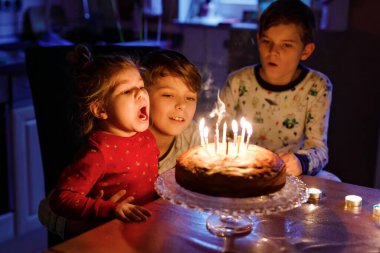 10. yaş gününü kutlayan sevimli çocuk. Küçük kız kardeş ve iki erkek kardeş pastaya mum üflüyorlar. Üç çocuklu sağlıklı bir aile portresi..