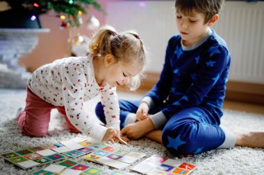 İki küçük çocuk, küçük tatlı kız ve okul çocuğu süslü Noel ağacında kağıt oynuyorlar. Mutlu sağlıklı kardeşler, erkek ve kız kardeşler birlikte eğleniyor. Aile Xmas kutlaması