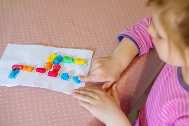 Küçük yaratıcı kız, oyuncaklarla renkli zürafalar yapıyor. Aktif mutlu çocuk çizim yaparken eğleniyor. Çocuklar için eğitim. Komik aktivite