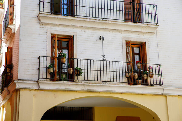 Decorative balconies and windows with gates of old city center house in Seville, Spain.
