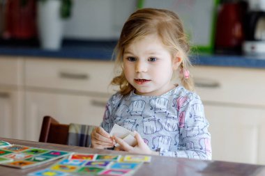 Heyecanlı, gülümseyen küçük kız iskambil oynuyor. Mutlu sağlıklı çocuk hafızasını eğitiyor, düşünüyor. Çocuk için evde yaratıcı bir eğlence ve eğitim. Evde aile aktivitesi