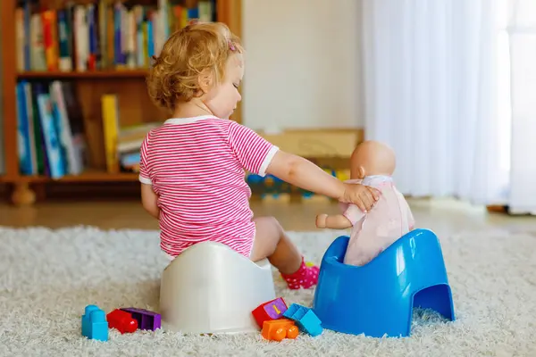 可爱的12个月大的幼儿女婴坐在便盆上的衣服 小孩玩洋娃娃玩具 厕所培训的概念 幼儿学习 发展步骤 — 图库照片