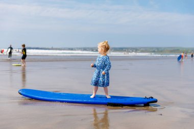 Ballybunion Sörfçü Plajı 'nda küçük şirin bir kız sörf tahtasında ilk kez eğleniyor, İrlanda' nın batı kıyısında. Mutlu çocuk ailesiyle İrlanda yazının tadını çıkarıyor.